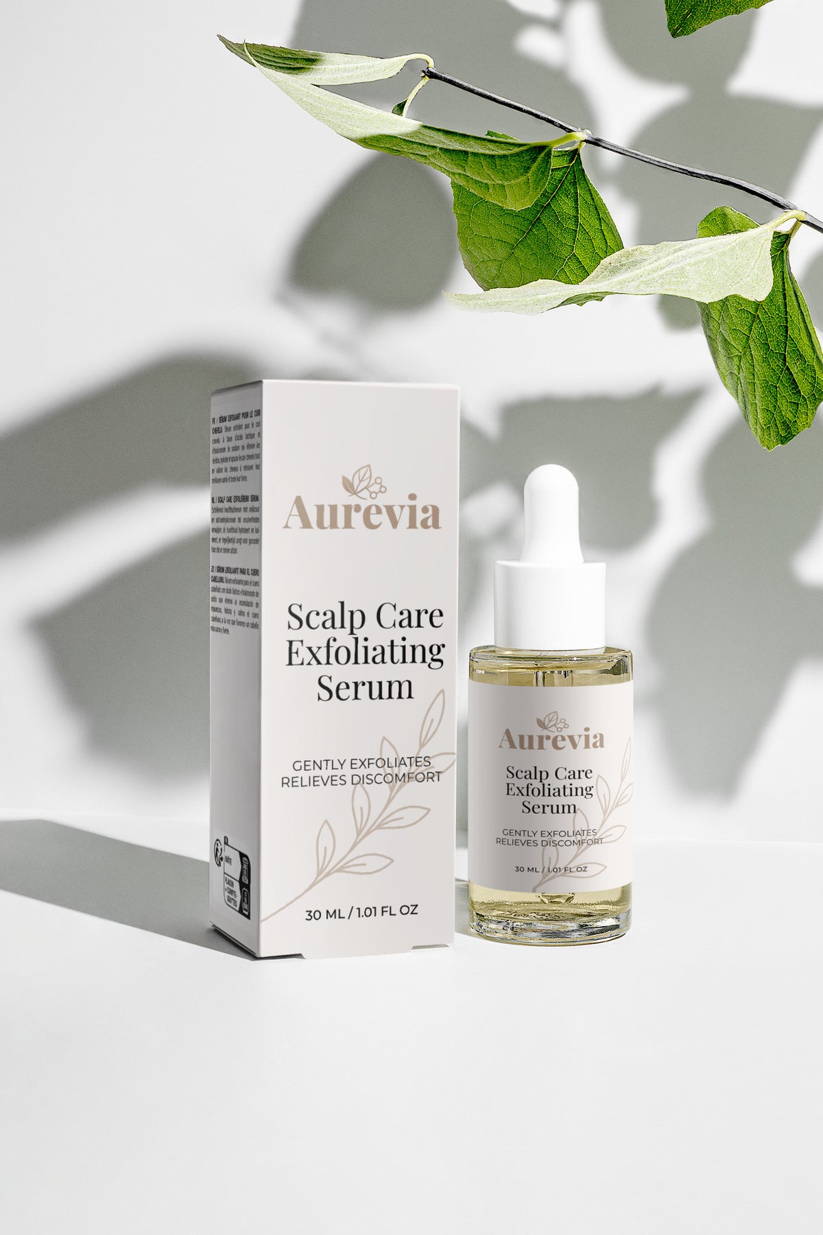Aurevia Scalp Care Exfoliating Serum bottle and box with green leaves, gently exfoliates and relieves discomfort