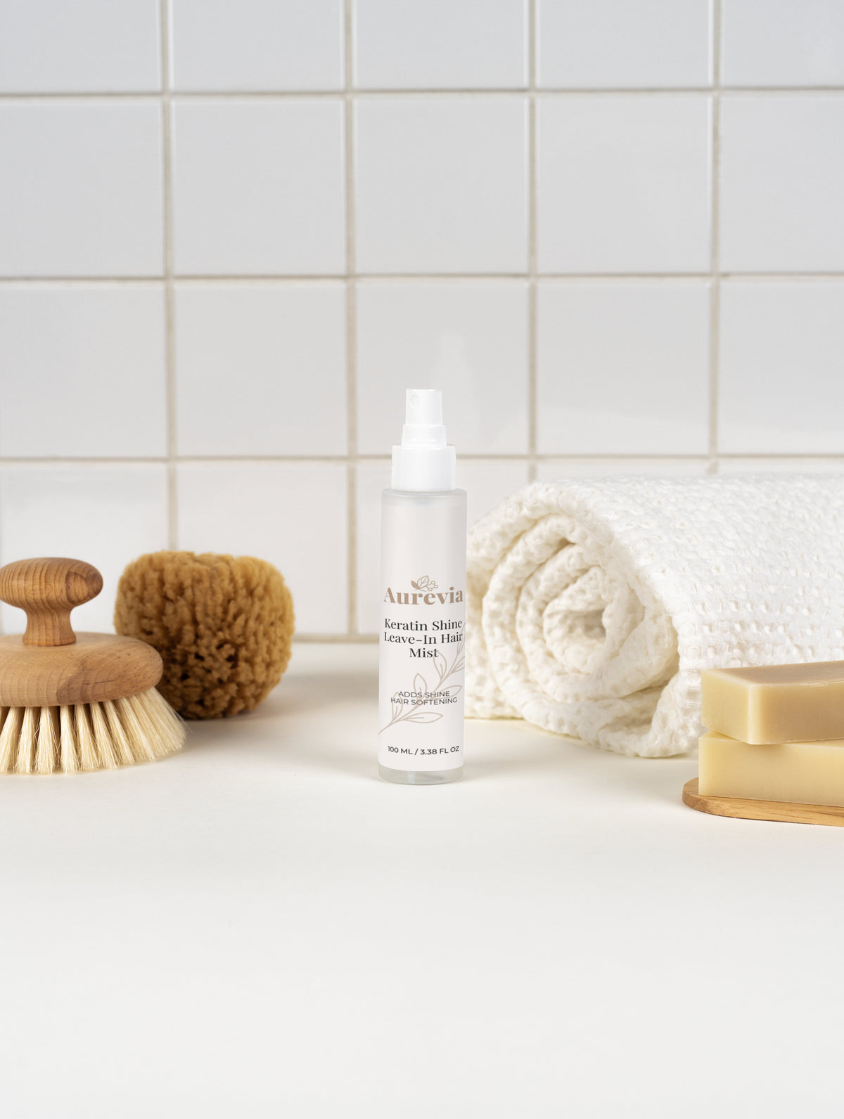 Keratin Shine Leave-In Hair Mist for soft, shiny hair care on bathroom counter with towel and brush